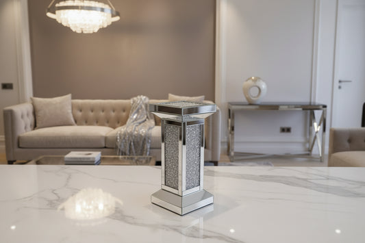 The Crystal Elegance Mirrored Pedestal Table is a small, rectangular table featuring crushed crystal panels and a glittering frame, shown against a plain white background.