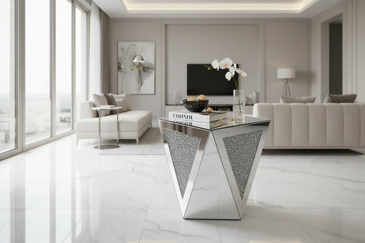 The Crystal Luxe Mirrored Accent Table features a geometric silver-toned design with triangular sections inset with a glittery texture, displayed against a plain white background.